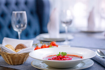 Beetroot soup, borscht, beautifully served in a white plate on the table in the restaurant. National Russian, Ukrainian cuisine. Restaurant menu