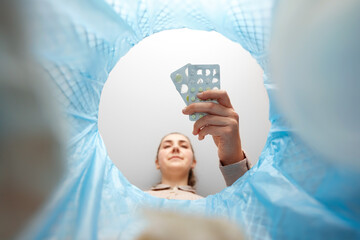 recycling, waste sorting and sustainability concept - woman throwing expired medicine pills into...