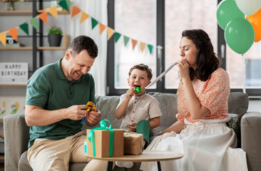 family, holidays and people concept - happy mother, father and little son with gifts and party blowers having fun and celebrating birthday at home