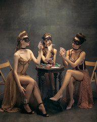 Pretty women in vintage 20s dresses. Young girls in art action sitting together and posing on wall...