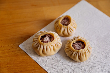 Steamed national Mongolian food dumpling Buuz filled with minced beef, white serviette, wooden table, Close up east Siberian Buryats dish poses, Juicy minced meat wrapped handmade dough shirt buuza