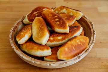 Delicious little fried pies with green onion and egg, patties or pirozhki, Traditional Russian pastry cuisine, Homemade cakes, white plate on wooden background, Food Slavonic concept rustic village