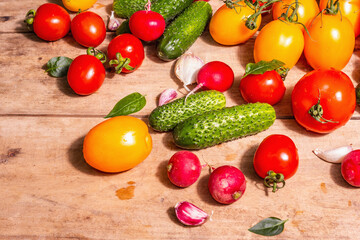 Assortment of ripe organic farmer red and yellow tomatoes, cucumbers, radish, garlic, and fresh basil leaves