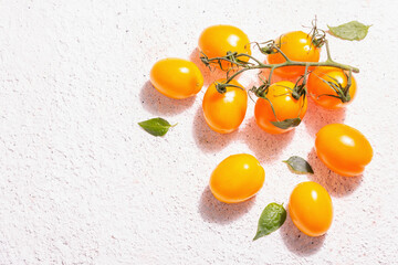 Yellow-orange tomatoes on light plaster background