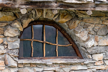 Fairy-tale oval window of a small stone house.