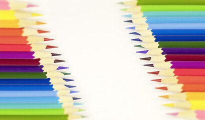 Fototapeta premium White background with colored pencils on both sides. Wooden colored pencils for drawing on paper, study concept.
