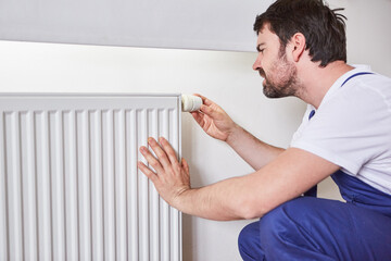 Do-it-yourselfer adjusts the thermostat on the radiator