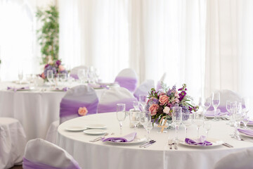 A flower arrangement stands on a festive table in a restaurant on the wedding day.
