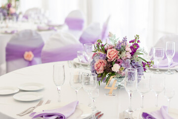 A flower arrangement stands on a festive table in a restaurant on the wedding day.