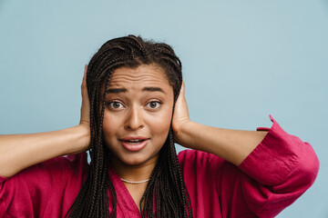 Young black shocked woman with pigtails covering her ears