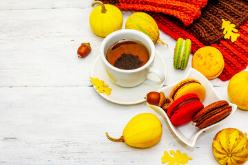 French macarons in autumn colors with cup of hot tea