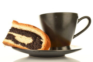 One fragrant freshly baked poppy roll slice on a black saucer with a cup, close-up, isolated on...