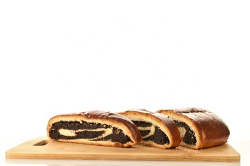 Freshly baked poppy seed roll, cut into slices on a wooden board, close-up, isolated on white.