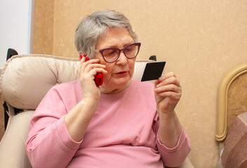 An elderly woman in casual clothes dictates her credit card details by phone