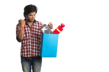Fototapeta na wymiar Young men showing rakhi on his hand with shopping bags and gift box on the occasion of Raksha Bandhan festival.