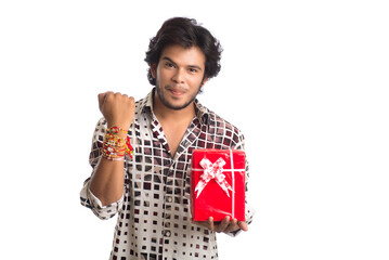 Man or Brother showing rakhi on his hand with shopping bags and gift box on the occasion of Raksha Bandhan festival.