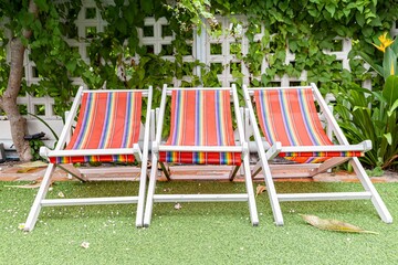 Wooden sun loungers with plastic cloth by the resort pool