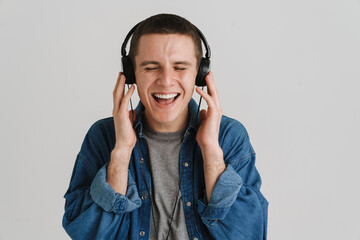 Young brunette man smiling and listening to music with headphones