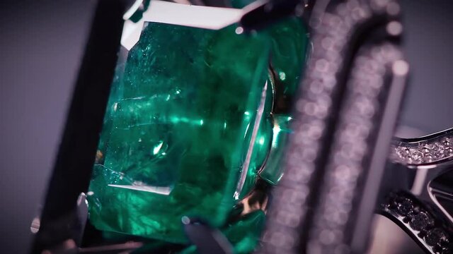 Close up of breathtaking platinum cufflinks with diamonds and emeralds. Video. Beautiful jewelry for man isolated on dark background under the spotlight.