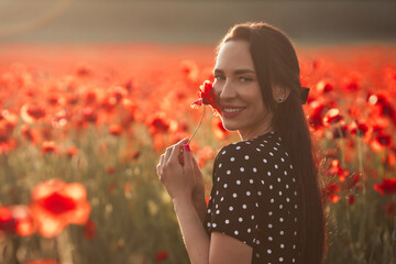 Young brunette woman 25-30 years old with long groomed hair in black dress white polka dots enjoy a...