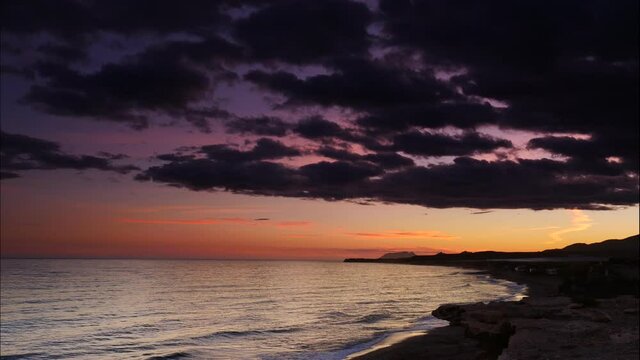 Sunset over sea. Time lapse of dark stormy clouds moving over Mediterranean coast of Spain.