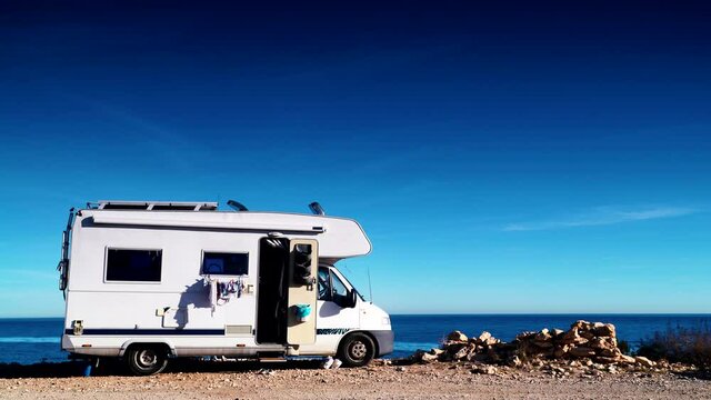 Camper car rv with clothes hanging to dry camping on sea shore. Holidays with motor home.