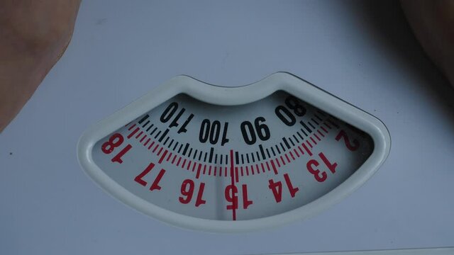 Male feet stepping on bathroom scales. Overweight man standing on weighing machine, about 100 kg. Health care, overload lose weight concept.
