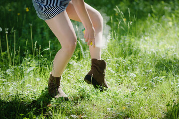 Woman applying mosquito repellent on the leg skin in the forest.