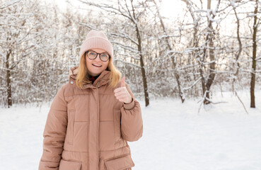 Fototapeta na wymiar Young beautiful happy girl in winter knitted hat posing in winter forest. Snow background