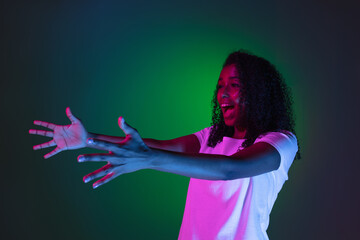 Young woman's portrait on gradient colors studio background in neon. Concept of human emotions.