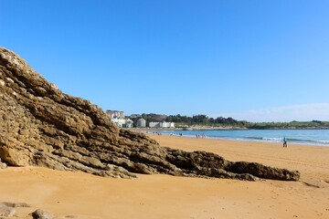 View along the beach with rock strata in the foreground on a sunny spring morning June 2021 Sardinero Santander Cantabria Spain