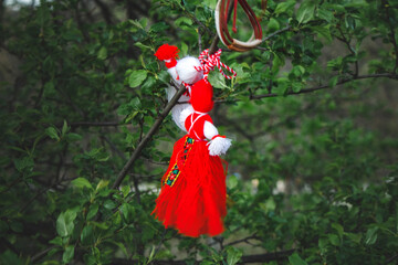 Girl and boy in White and red made of yarn hung on a green tree, a tradition in Bulgaria in the spring