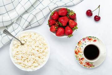 Quark, a cup of black coffee and strawberry on a white table. Hot morning drink. Russian tvorog and red berries, breakfast concept. Healthy food. Top view. Flat lay composition.