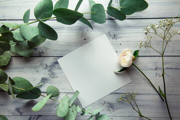blank white sheet with place for text on a light background with plant leaves, flowers and...