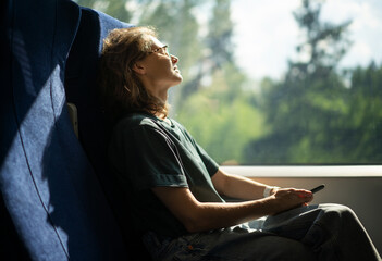 Young beautiful woman wearing glasses sitting in a chair in a high-speed train relaxing while traveling - Powered by Adobe