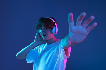 Caucasian young man's portrait on dark studio background in neon. Concept of human emotions, facial...