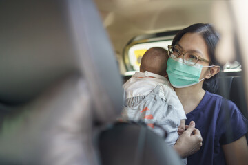 Fototapeta na wymiar Asian Young Mother wearing Protective face mask holding adorable newborn little baby boy sitting in the car