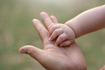 Asian Father touching and holding Little tiny Baby hand at outdoor together