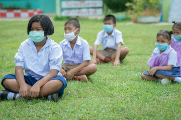 Surin, THAILAND - October 10, 2020:Thai students are sitting in a row to keep social distancing They are aware of Covid-19 and keep social distancing and wearing protective facemasks at school during 