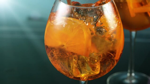 Super slow motion. Ice cube falling into glass of orange cocktail. Aperol spritz. Filmed on high speed cinematic camera at 1000 fps.