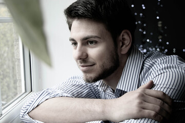 Portrait of handsome man with beard sitting next to window