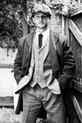 Handsome English gangster smoking at railway station with train in the background