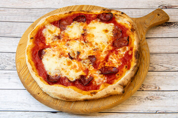 Italian pizza with salami and lots of cheese and thin wheat flour dough served