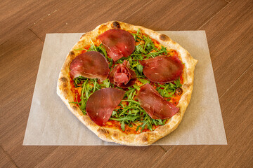 Tyrolean pizza with carpaccio meat, arugula, tomato and thin crust