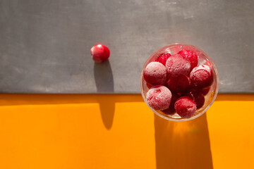 Cherry in ice crystals. Gray orange background. Hard light. Top view. Copy space. 