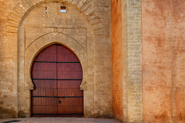Fototapeta na wymiar Arabic door Bab laalou in the wall of the medina of Rabat in Morocco. Reddish varnished wood