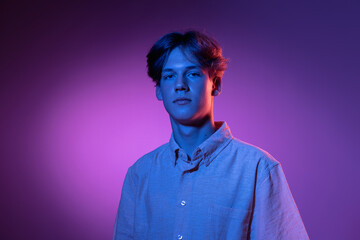 Serious. Handsome caucasian man's portrait isolated on purple studio background in neon, monochrome. Beautiful male model.