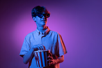 Excited in 3D eyewear and with popcorn. Caucasian man's portrait isolated on blue studio background...
