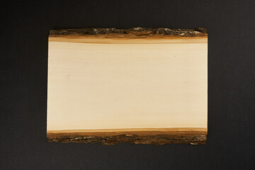Rectangle slab of wood with bark on back background.                                  
