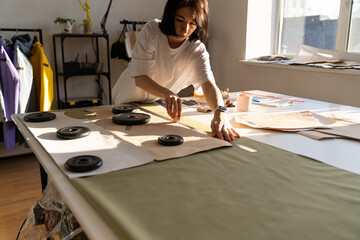 Woman seamstress use chalk and ruler to draft paper patterns on textile material for clothes sew....